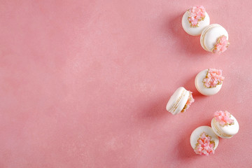 Fototapeta na wymiar Minimalistic composition with bunch of white french macaron sweets with pink crystal shaped marmalade decoration over grunged concrete texture background. Top view, close up, flat lay, copy space.