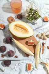 Cut appetizing ripe melon and drinks in stained-glass glasses on a table with a blue tablecloth.