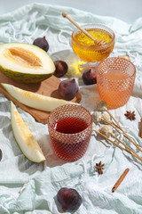 Cut appetizing ripe melon and drinks in stained-glass glasses on a table with a blue tablecloth.