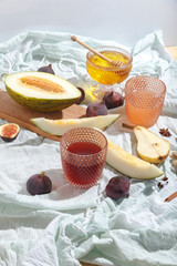 Cut appetizing ripe melon and drinks in stained-glass glasses on a table with a blue tablecloth.