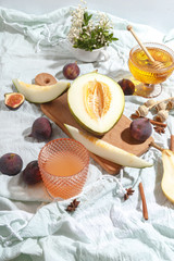 Cut appetizing ripe melon and drinks in stained-glass glasses on a table with a blue tablecloth.