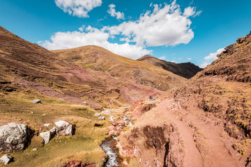 Fototapeta na wymiar Trekking through the Red Valley, Vinicunca Rainbow Mountain, Cusco, Peru an amazing landscape scenery with colorful mountains and red hills with Alpaca and farmers of the Andean civilisation