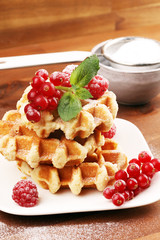 Traditional belgian waffles with fresh mint, sugar and raspberries on table