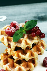 Traditional belgian waffles with fresh mint, sugar and raspberries on table