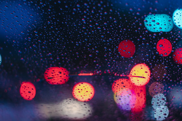 Drops of rain on car glass background, Street night bokeh lights, Selective focus.