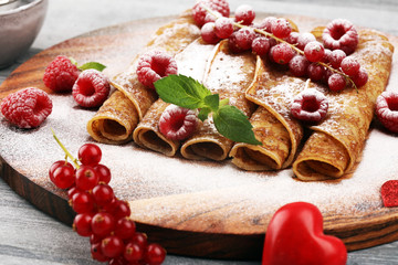 Delicious Tasty Homemade crepes or pancakes with raspberries and mint on rustic background