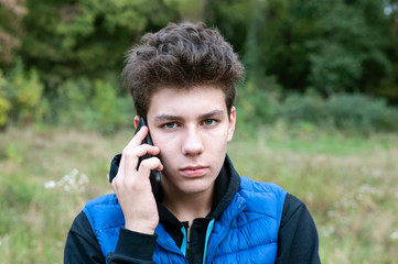 Handsome teenage boy talking on the phone, long listens to his father's instructions on the phone