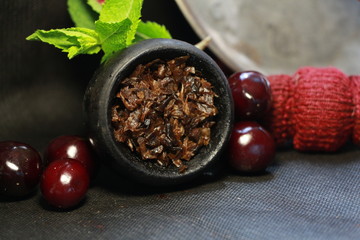 bowl with tobacco for hookah. berries on a black background