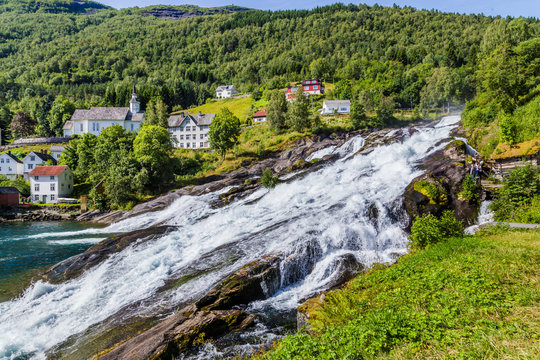 Panorama of small village Hellesylt with Hellesyltfossen waterfall in along Geiranger fjord in More og Romsdal county in Norway