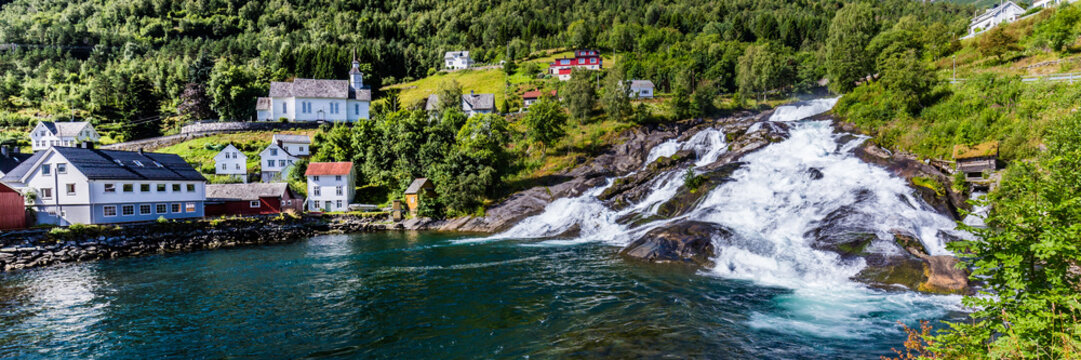 Panorama of small village Hellesylt with Hellesyltfossen waterfall in along Geiranger fjord in More og Romsdal county in Norway