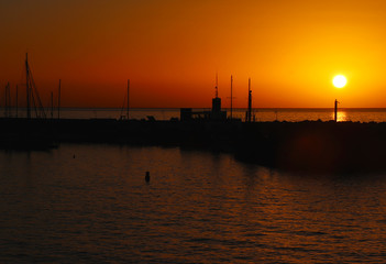 Boat and rock silhouette with orange and red sky and ocean water in Spain