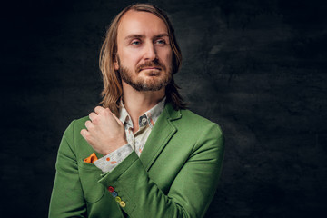 Portrait of sceptical creative man in green blazer on the dark background.