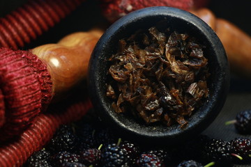 bowl with tobacco for hookah. fruits and berries on a black background. smoke hookah