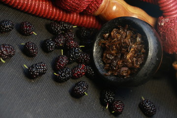 bowl with tobacco for hookah. fruits on a black background. smoke hookah