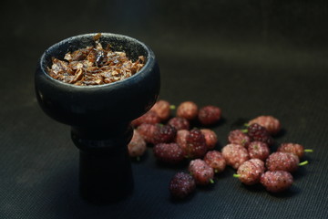 bowl with tobacco for hookah. berries on a black background