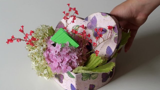 Valentine Gift. Young Hands with hearth gift box with flowers and message. St. Valentine’s Day Love concept