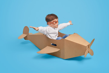 Little aviator flying in carton plane