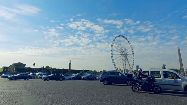 Traffic vehicles crossing the Place de la Concorde. In the background Obelisk and Ferris Wheel in Paris, France