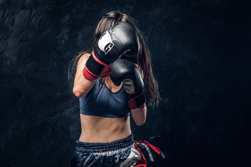 Strong kick with boxing gloves from sportive brunette female boxer.