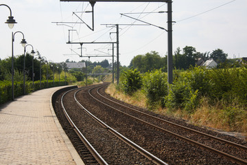 Fototapeta na wymiar Train track view with a curve, surrounded with green shrubbery