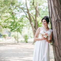 Beautiful bride with stylish make-up in white dress in spring garden 