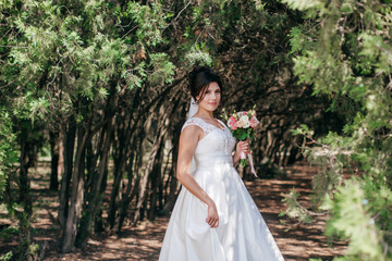 Beautiful bride with stylish make-up in white dress in spring garden 
