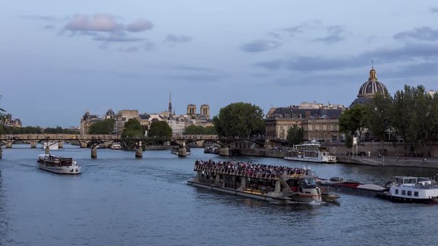 Nightfall over Seine River, Ile de la Cite, Pont des Arts, Notre Dame and Institut de France - Paris, France. Timelapse with boat traffic.
