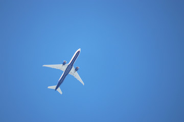 Airplane flying in the clear blue sky, bottom view. Commercial plane taking off