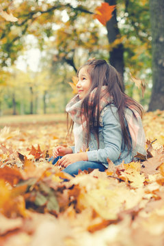 hübsches, kleines Mädchen mit braunen Haaren im Park im Herbst 