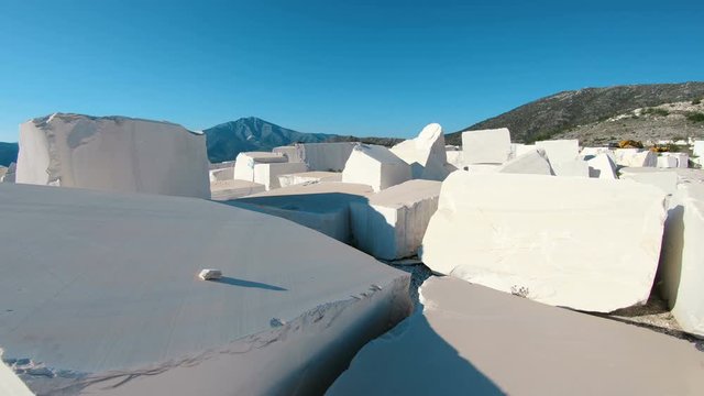 Walk POV at industrial marble quarry site with huge marble blocks