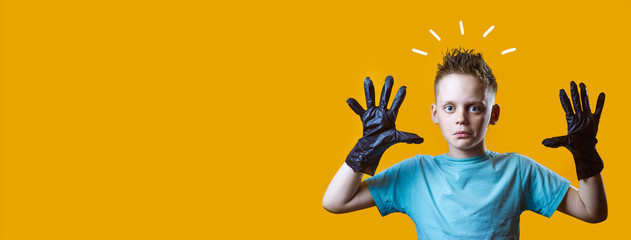 surprised boy in black gloves and blue t-shirt on a yellow background