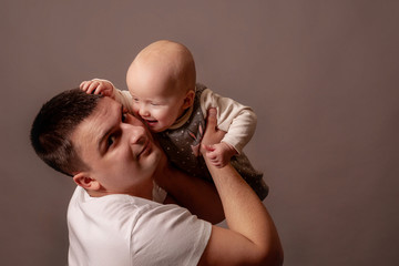 One year old daughter in her father's arms. Dad plays with baby, nurses her.