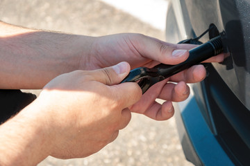 A man spins a hook for towing in front of a car. Car breakdown and towing.