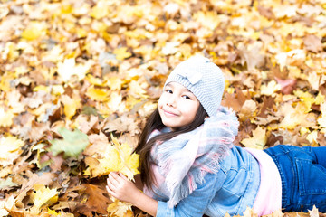 hübsches, kleines Mädchen mit braunen Haaren im Park im Herbst 
