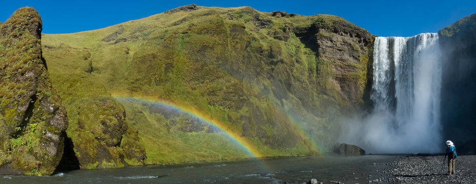 Photographer shooting double rainbow at Skogafoss Falls in southern Iceland. - Powered by Adobe