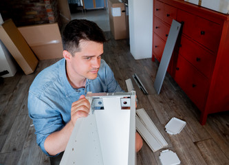 Young man with screwdriver instaling a furniture