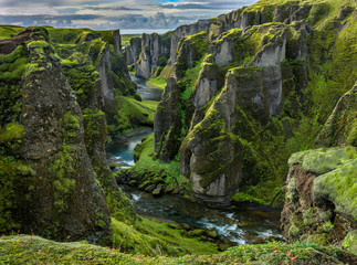 Fjaðrárgljúfur Canyon in southern Iceland. The canyon was carved through the lava and palagonite by progressive erosion by  the Fjaðrá River, fed by meltwater from glaciers over millennia.
