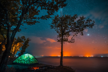 Small tent and tree on the shore. Night landscape. 
