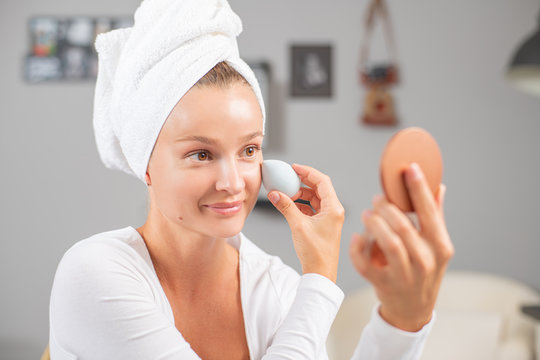Beautiful woman with perfect healthy skin is applying foundation for face.