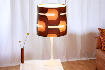 a vintage midcentury lamp from the 60s with a large brown lampshade standing on a cocktail table in the living room of a  loft luminous brown white pedestal lit bedside lamp  interior design warm HQ