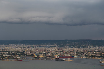 Fototapeta premium The city of Varna during the storm. The downpour is approaching the sea coast. The Bulgarian resorts in the summer. European recreation area. Thunderhead covers the city. 