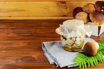 Marinated mushrooms in a jar on a wooden table. Fermented food.