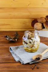 Marinated mushrooms in a jar on a wooden table. Fermented food.
