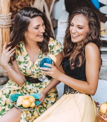 Portrait of two beautiful young women in a summer arbor with fruits