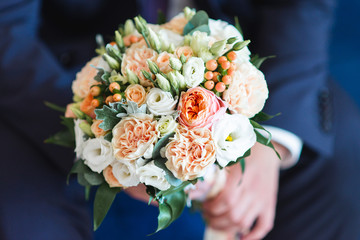 Elegant wedding bouquet in groom hand, beautifully decorated flowers closeup