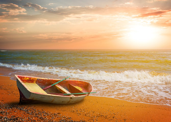 small boat on a sandy sea beach at the sunset