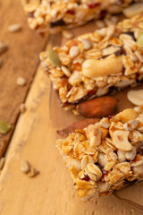 granola bars and nuts on a wooden background with space for design, vertical photo, diet, proper nutrition