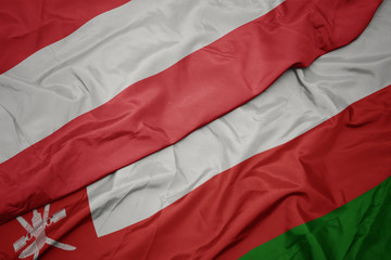 waving colorful flag of oman and national flag of austria.