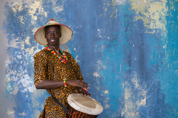 African man in traditional clothes playing djembe drum