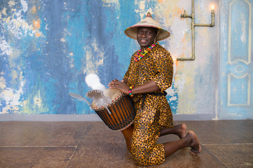 Handsome african drummer weared in traditional costume playing on djembe drum